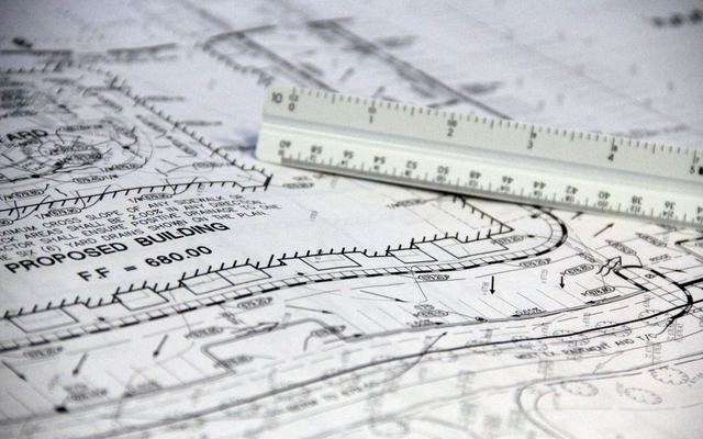Detailed close-up of architectural blueprints with scale ruler, showing building plans and measurements.